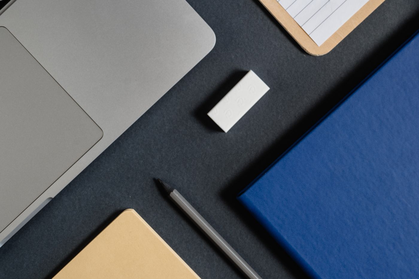 Laptop, caderno e materiais de trabalho organizados sobre a mesa, as ferramentas do Educador Financeiro
